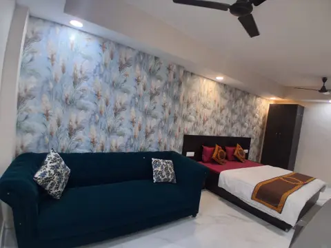 Furnished room with velvet sofa, double bed and wardrobe at Gurugram Stayz